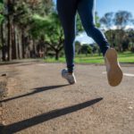 Close up on someone's feet as they run on a paved path outdoors.