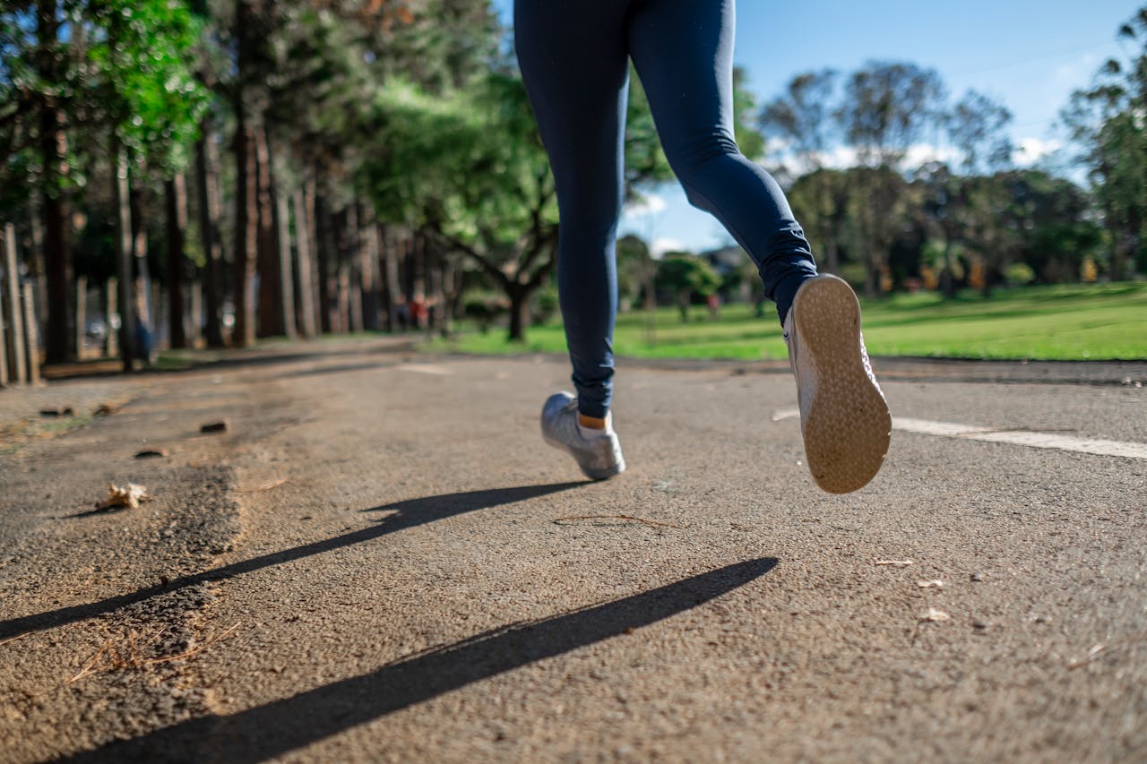 Close up on someone's feet as they run on a paved path outdoors.